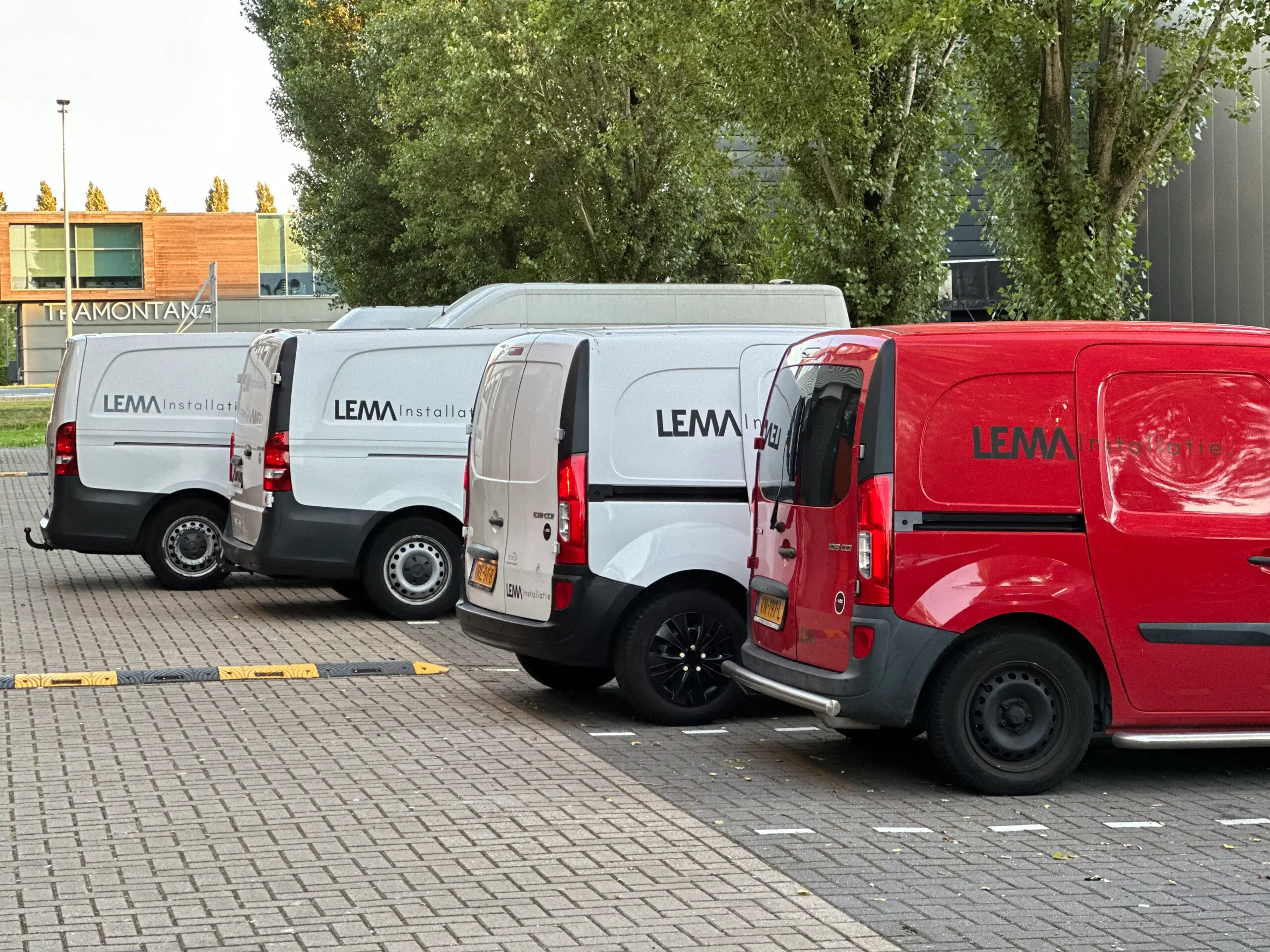 Vier bedrijfsbussen van LEMA Installatie op een rij, met het woordmerk duidelijk op de zijkant; de rechter bus is rood.