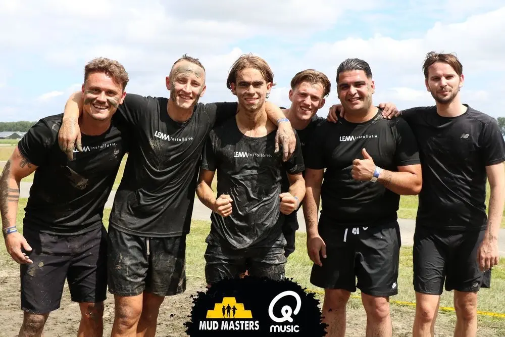 Zes teamleden van LEMA Installatie in bedrijfsshirts, onder de modder na afloop van een obstakelrun.